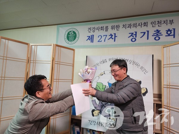 정갑천 전 회장이 박성표 신임 회장에게 꽃다발을 전달하고 있다.